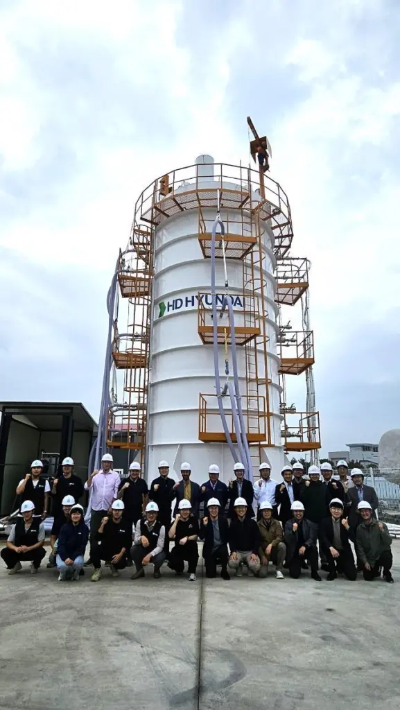 Workers in white hard hats in front of an HD KSOE LH2 vacuum tank