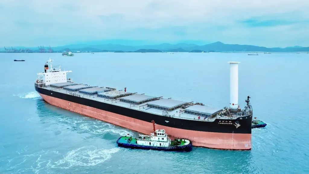 Bulk carrier Yodohime at sea featuring a single Rotor Sail at its bow and a tugboat alongside