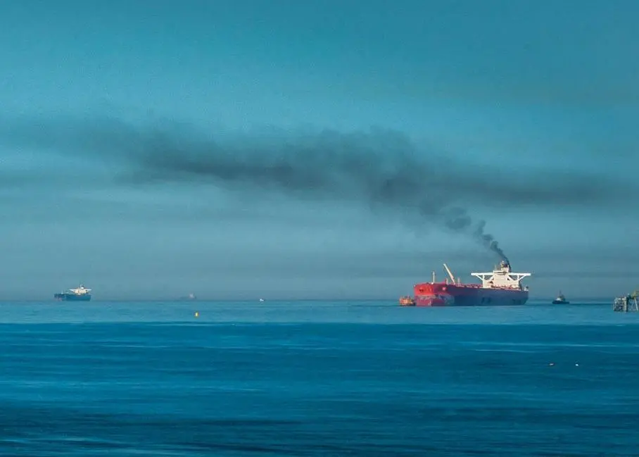 A ship at sea emitting black smoke