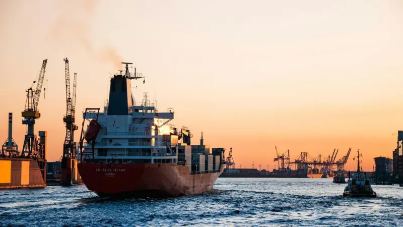 Container ship coming into port with cranes in the background
