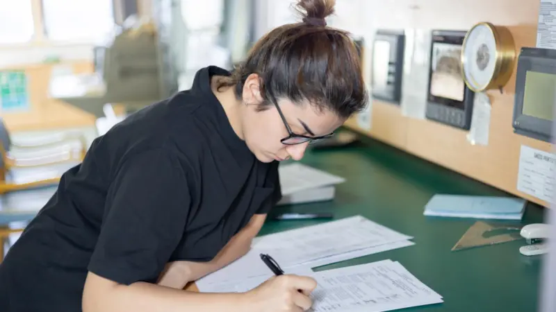 The image shows a worker looking at shipping data