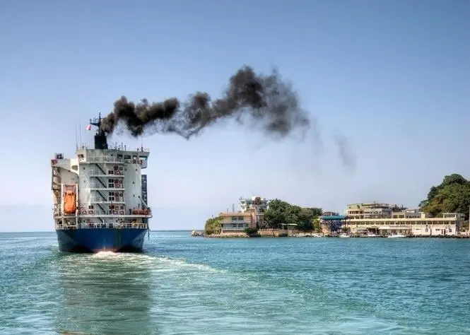 Ship emitting black smoke as it passes land