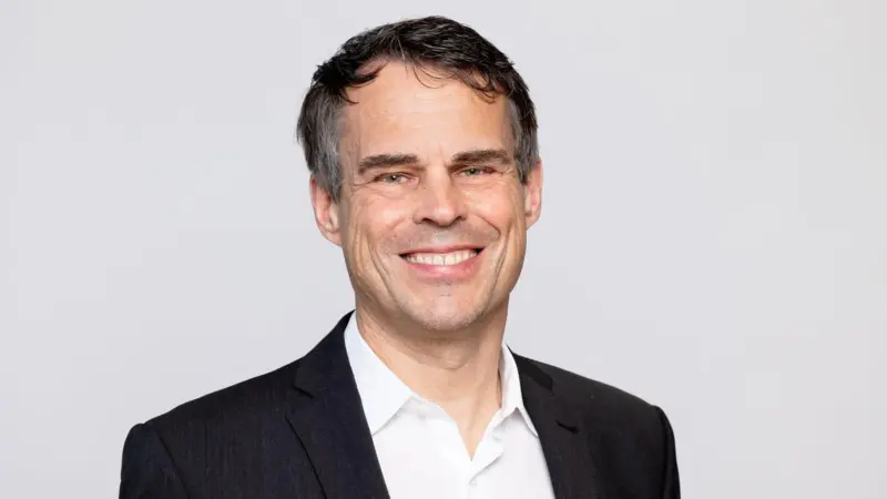 The image shows a headshot of Daniel Bischofberger, CEO of Accelleron smiling at the camera