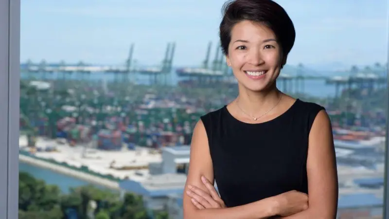 The photo shows Lynn Loo smiling for the camera in front of a port back drop