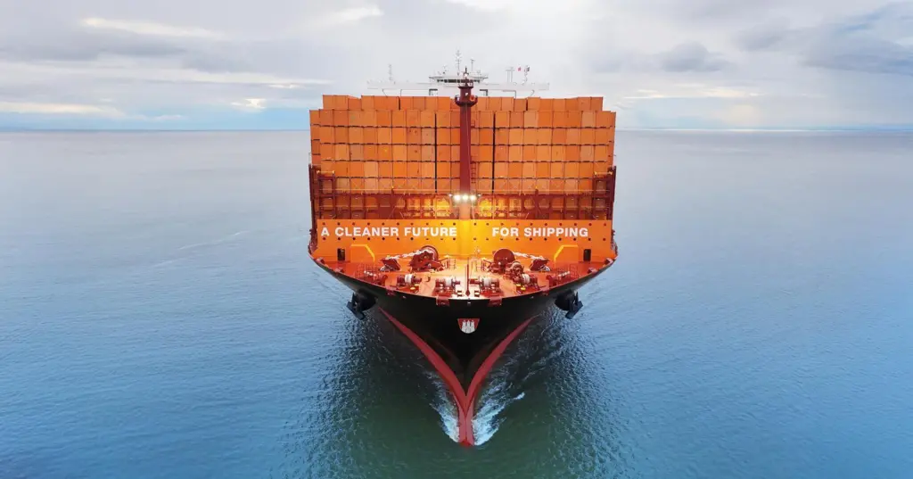 Container ship at sea full of orange containers saying 'A CLEANER FUTURE FOR SHIPPING'
