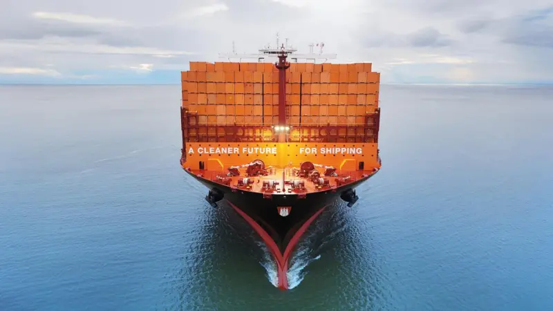 Container ship at sea full of orange containers saying 'A CLEANER FUTURE FOR SHIPPING'