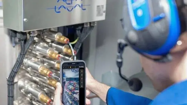 An Alfa Laval engineer working on some equipment and looking at a smart phone screen