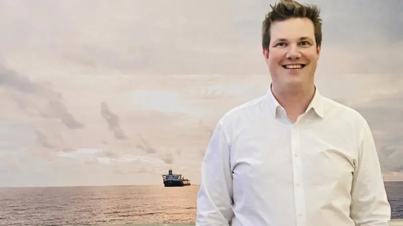 The image shows Martin White, CEO of Stream Marine Training in front of a shipping background