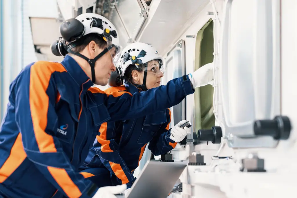 Two Wärtsilä workers looking into a ship's porthole