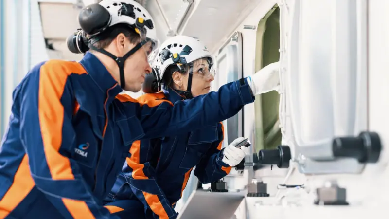 Two Wärtsilä workers looking into a ship's porthole
