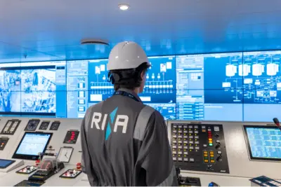 Man in hard hat and RINA boilet suit looking at ship bridge equipment